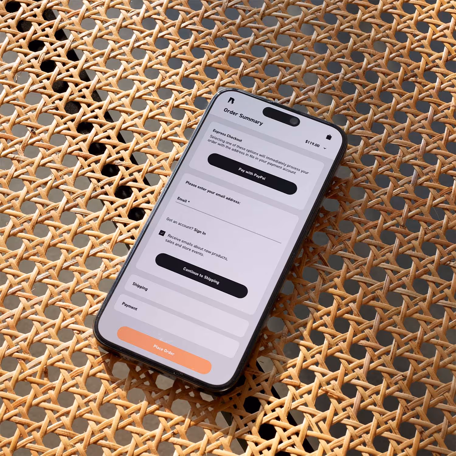 phone on wicker table displaying e-commerce website