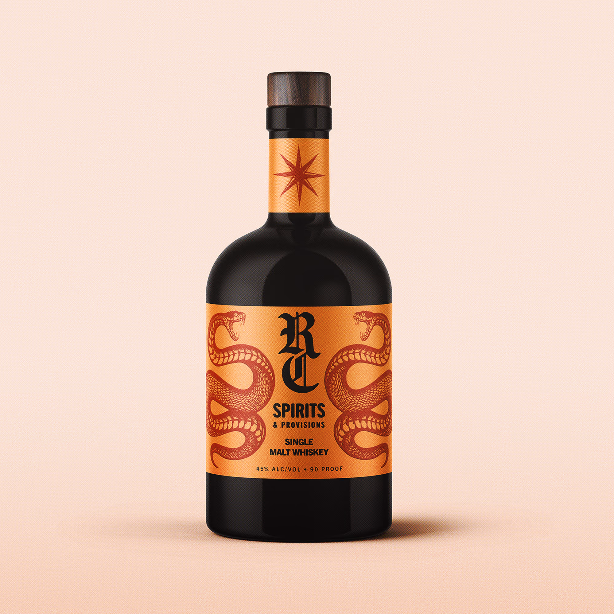 Dark bottle of RC Spirits single malt whiskey with an orange label featuring two red snakes facing each other, black gothic text RC Spirits & Provisions, and details 45% alc/vol, 90 proof, with an eight-pointed star on the neck label.
