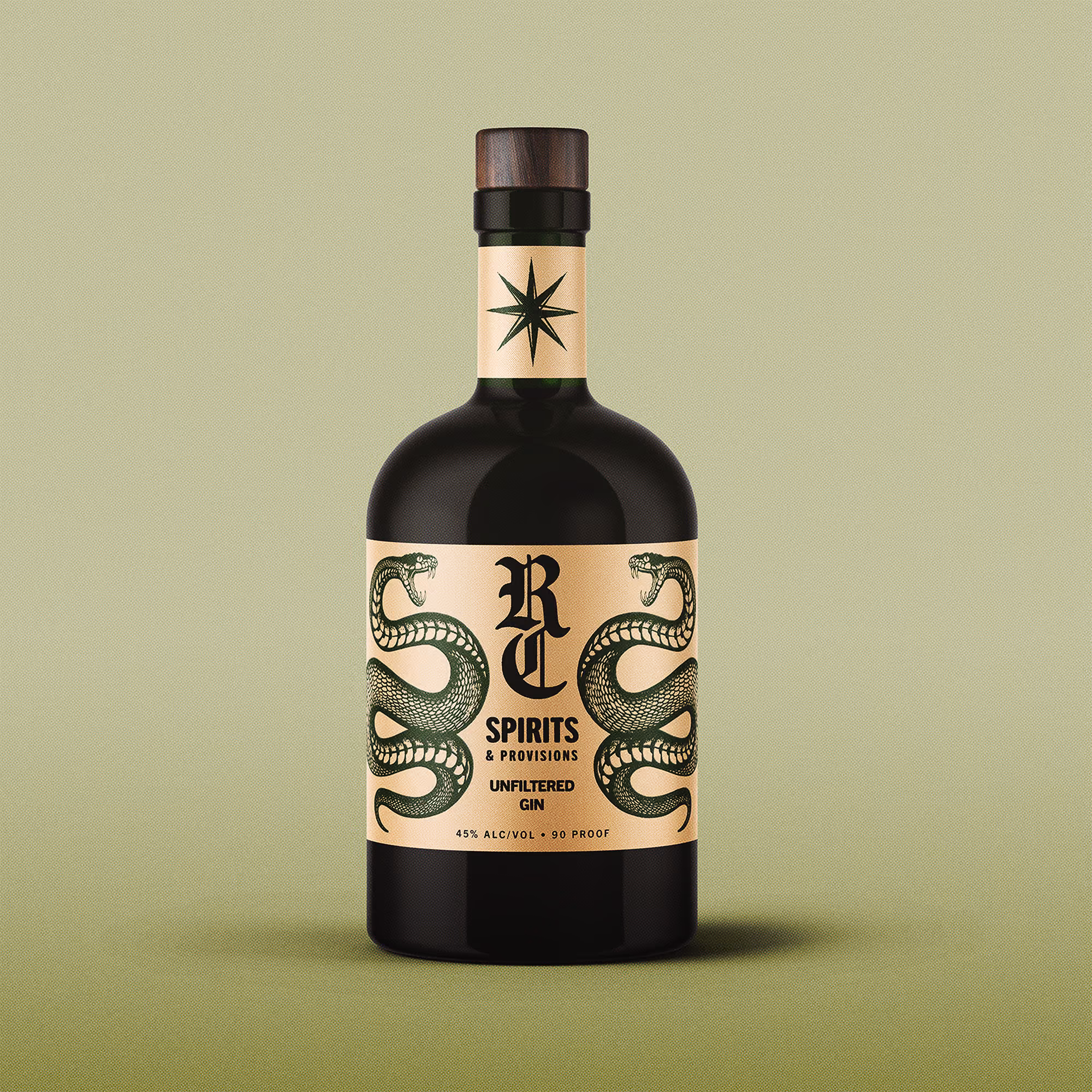 Dark bottle of RC Spirits & Provisions unfiltered gin with a beige label featuring two green snakes facing outward and a star symbol on the neck label, against a muted green background.