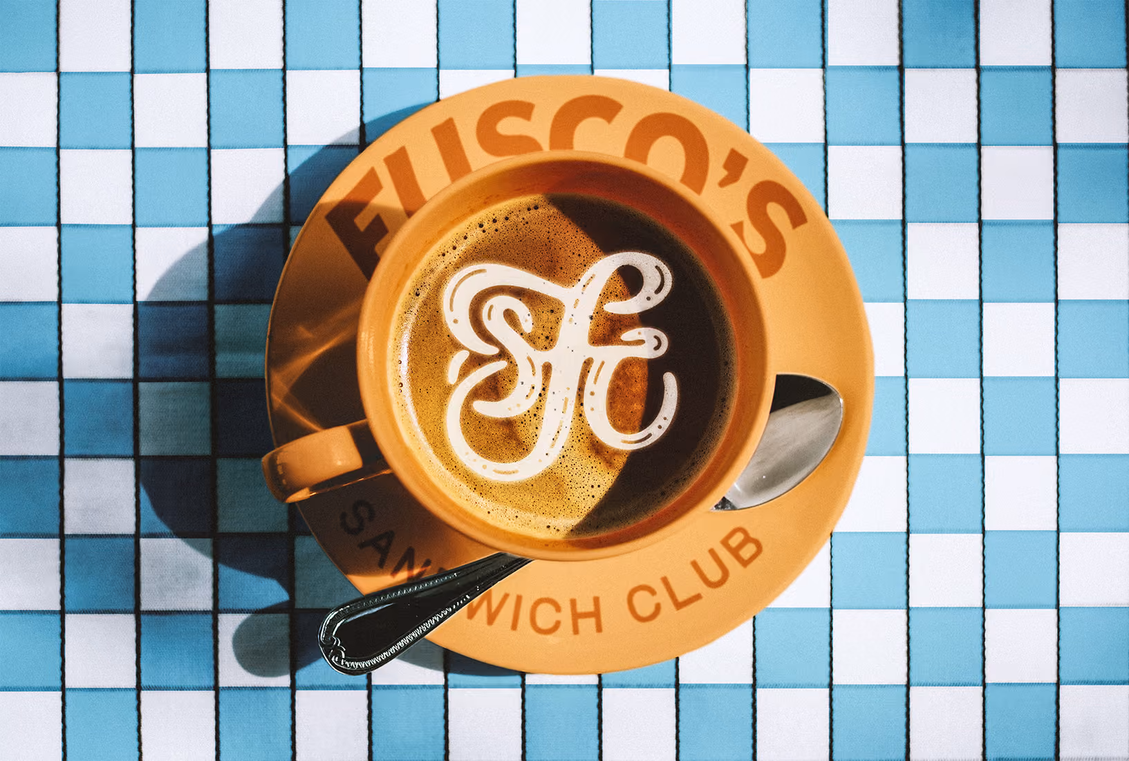Orange ceramic latte mug on blue and white checkerboard table covering