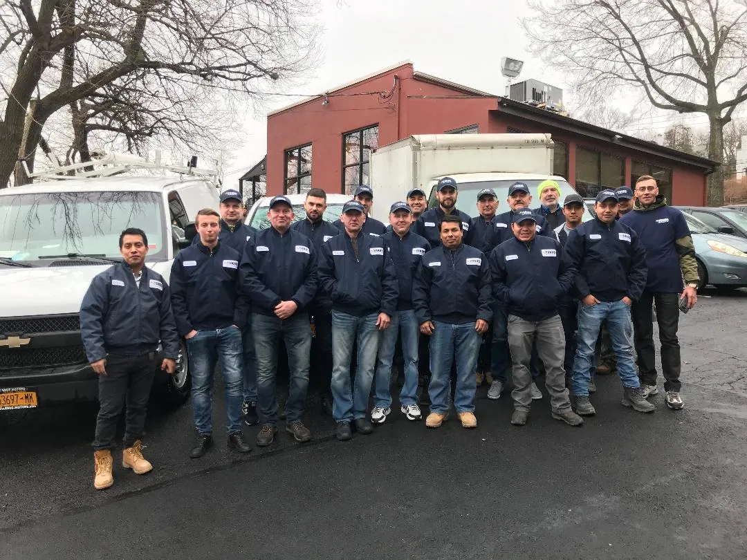 Yukos Mechanical HVAC team standing in front of service vehicles in New York.