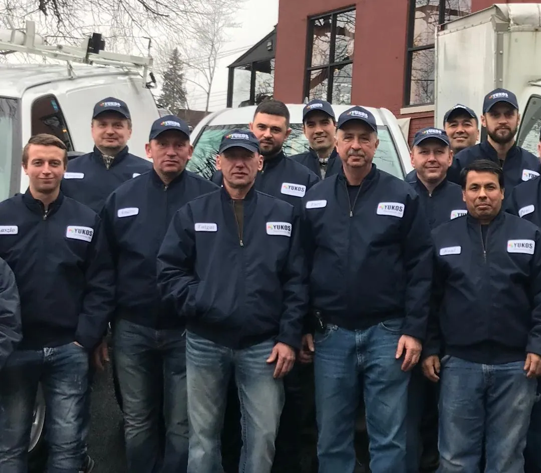 Yukos Mechanical team of HVAC technicians in uniform posing outside service vans.