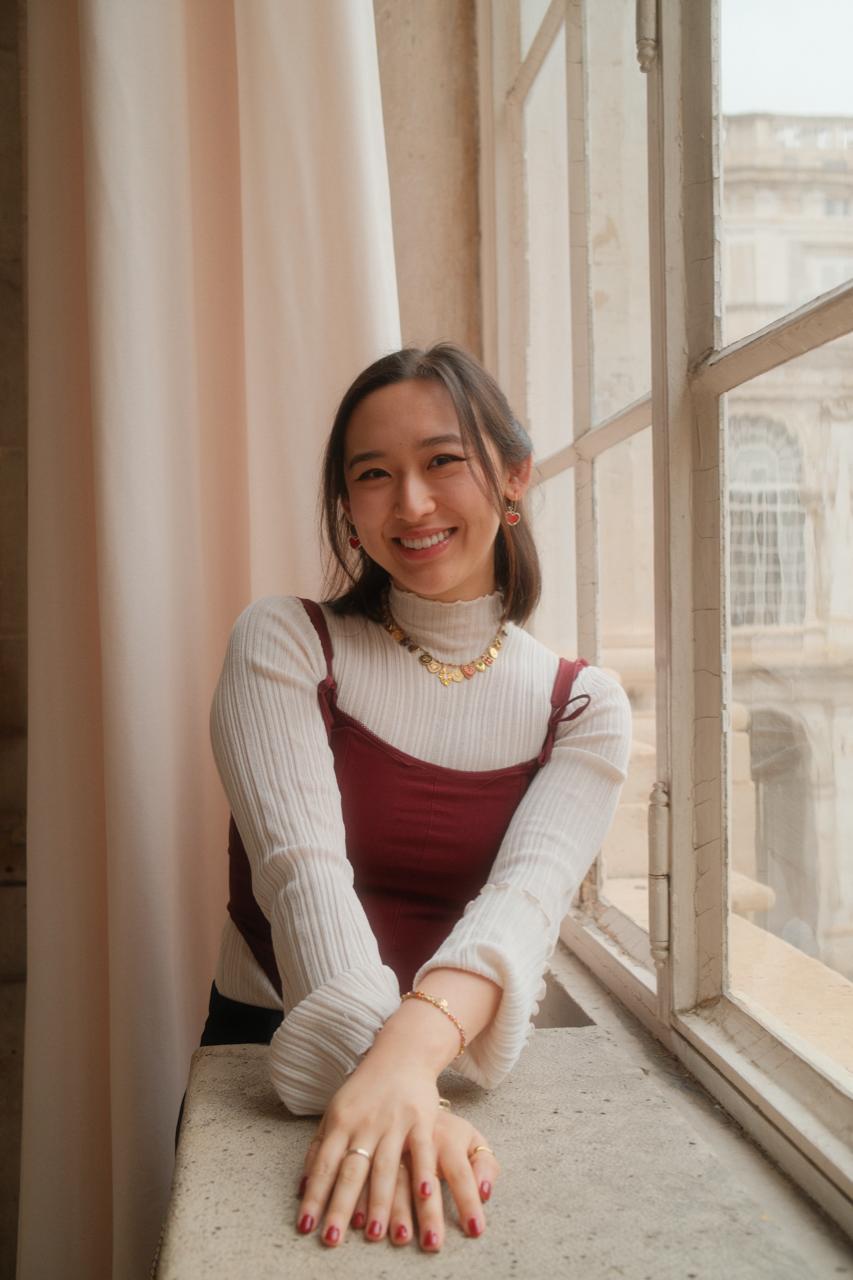 Profile picture of Alyssa. Girl with short, dark hair, bright smile, and hands outstretchced on the table.