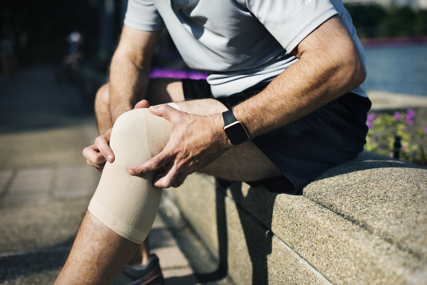 An athlete holds his bandaged knee during rehabilitation after a sports injury.