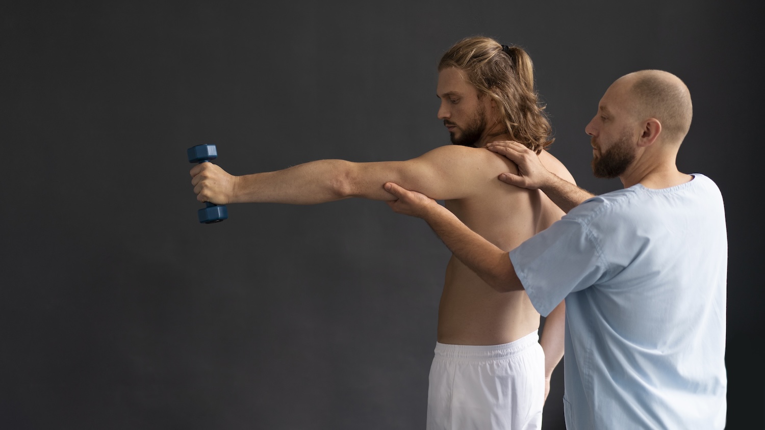 Physiotherapeut begleitet eine Schulterübung mit Kurzhantel bei Frozen Shoulder