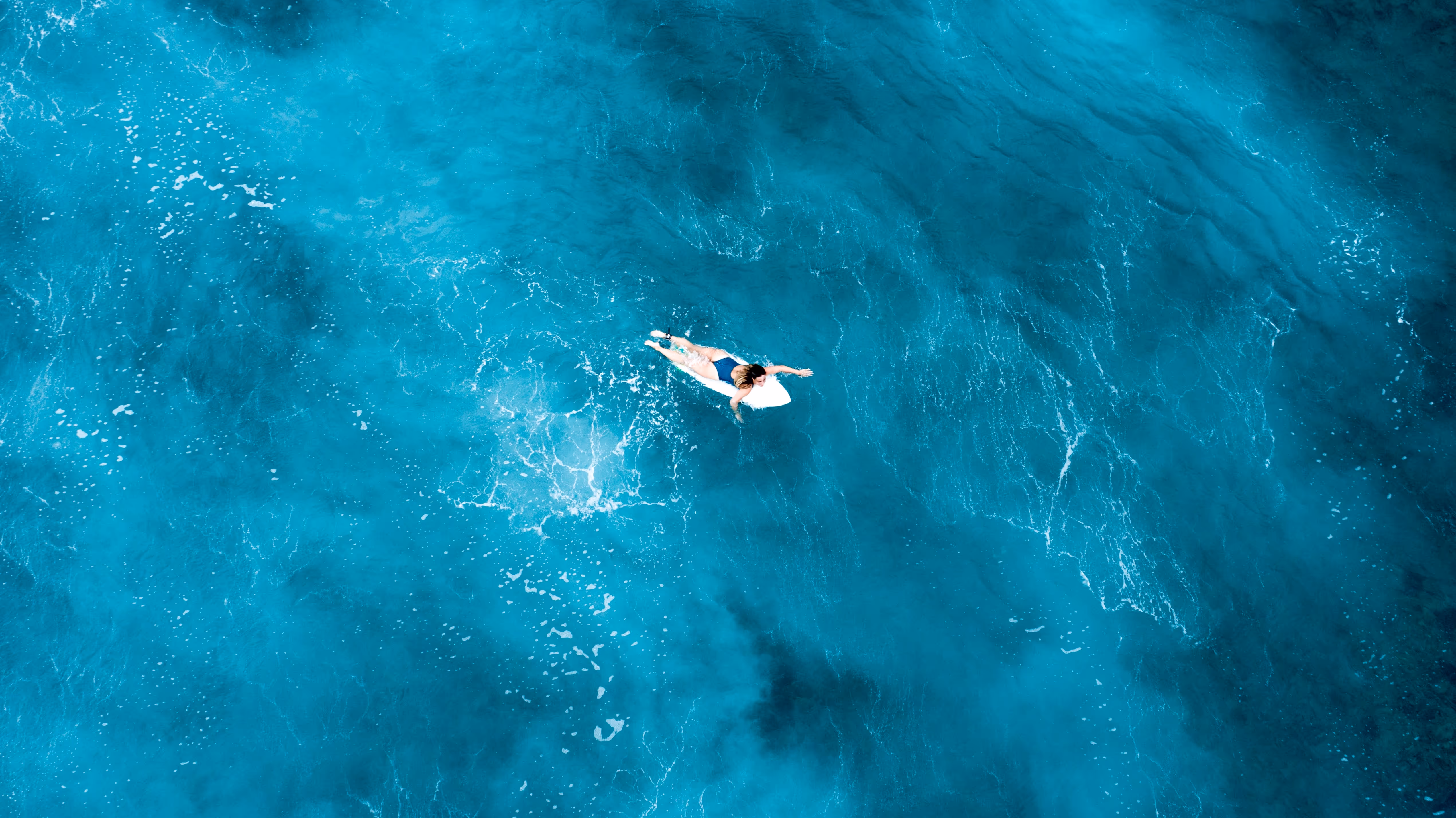 girl-laying-surfboard-floating-open-sea-with-crystal-clear-water-maldives