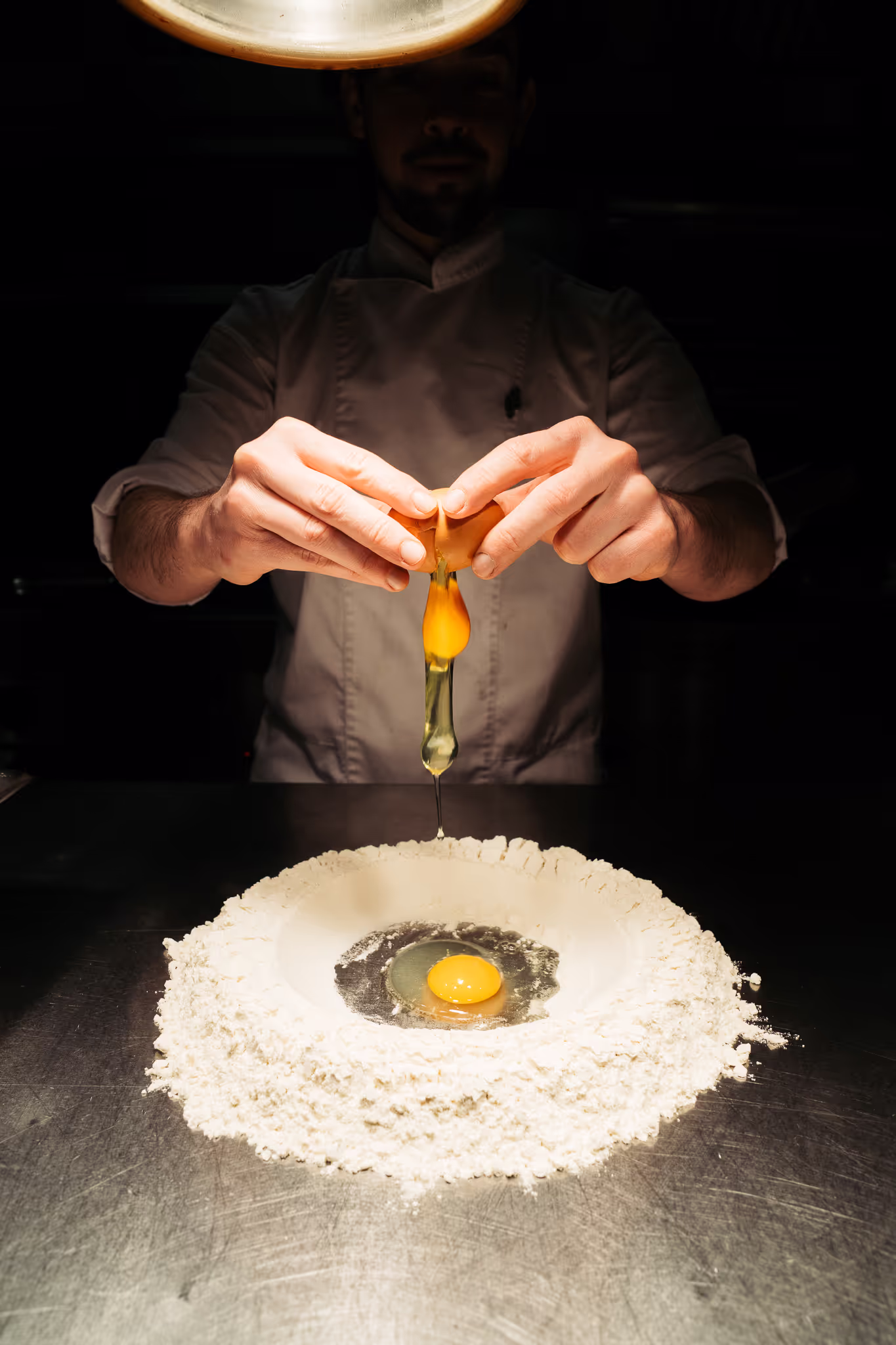 Foto van een chefkok die een pastadeeg aan het voorbereiden is.