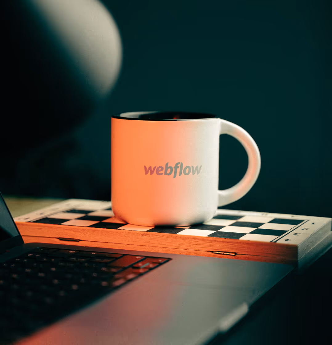En kaffekopp med Webflow logotyp som står på ett schackbäde