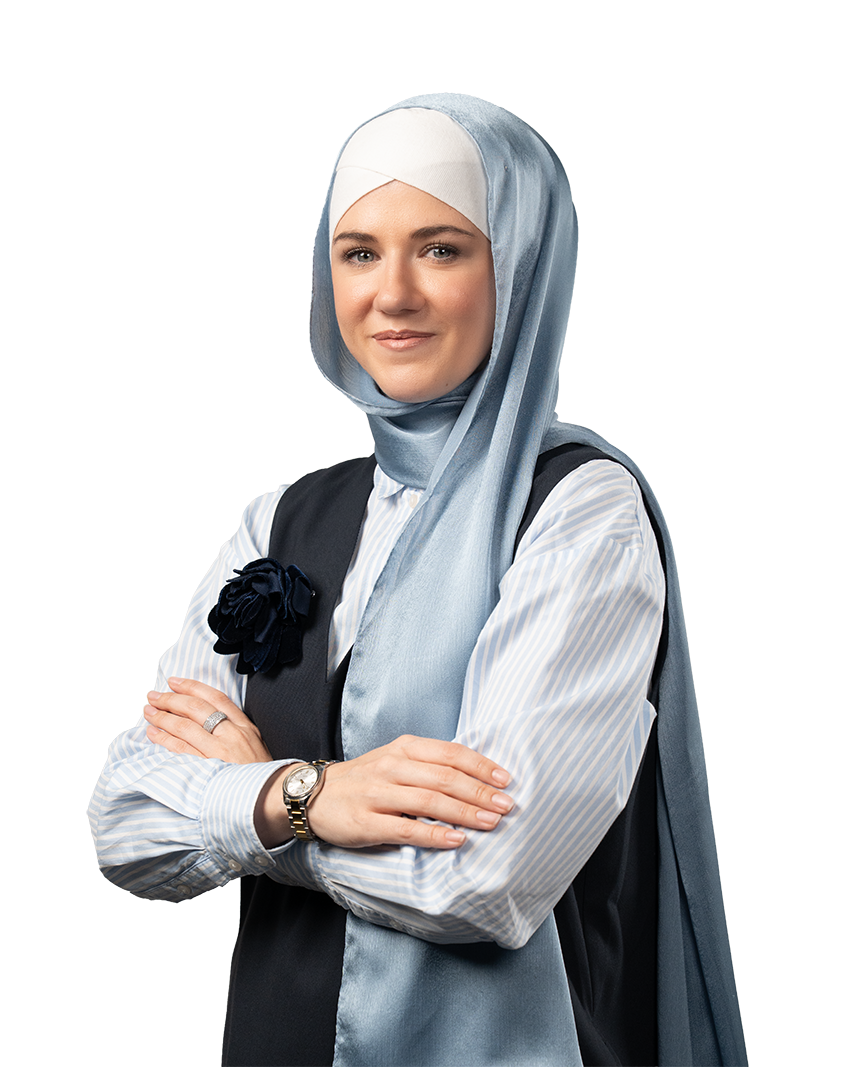 Confident woman wearing a light blue hijab, striped shirt, and dark vest with arms crossed.