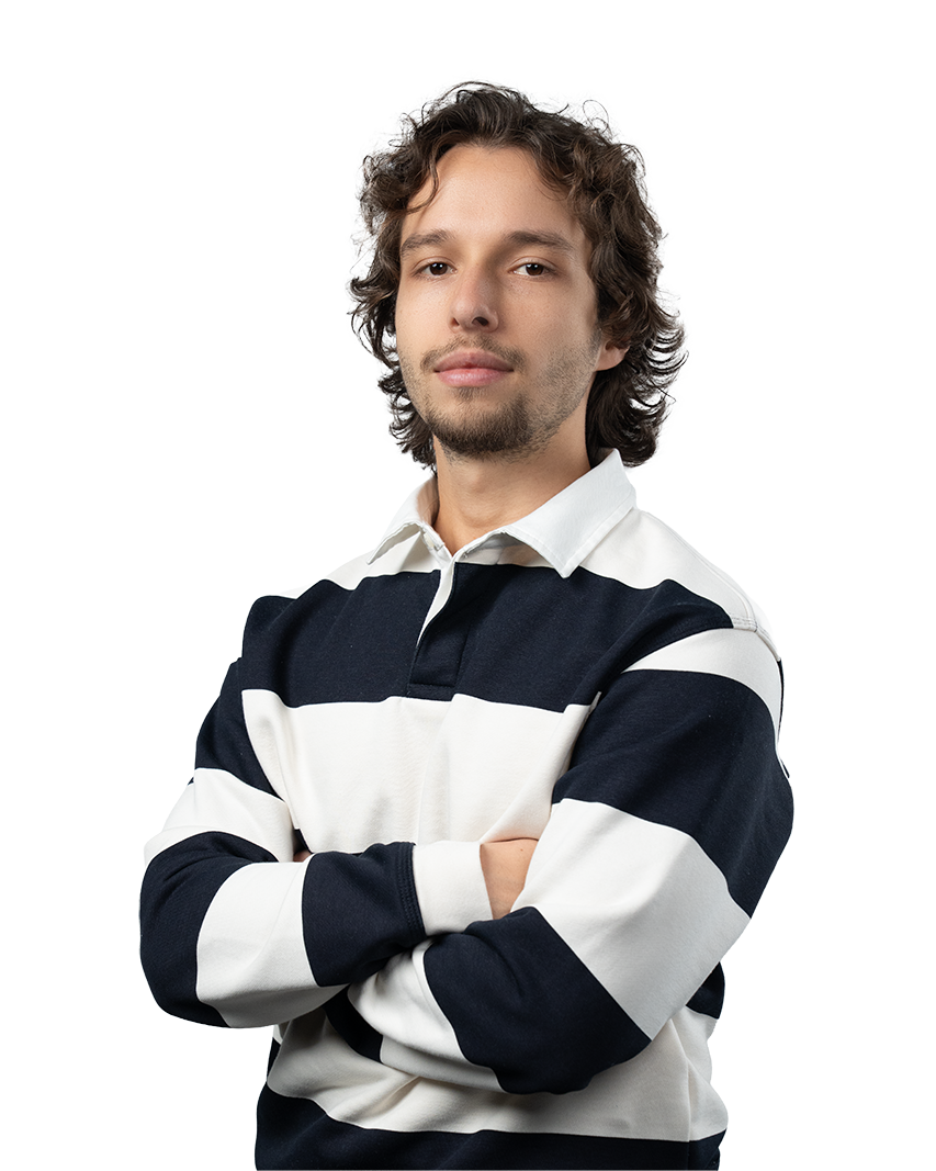 Young man with curly hair and light facial hair wearing a black and white striped rugby shirt with arms crossed.