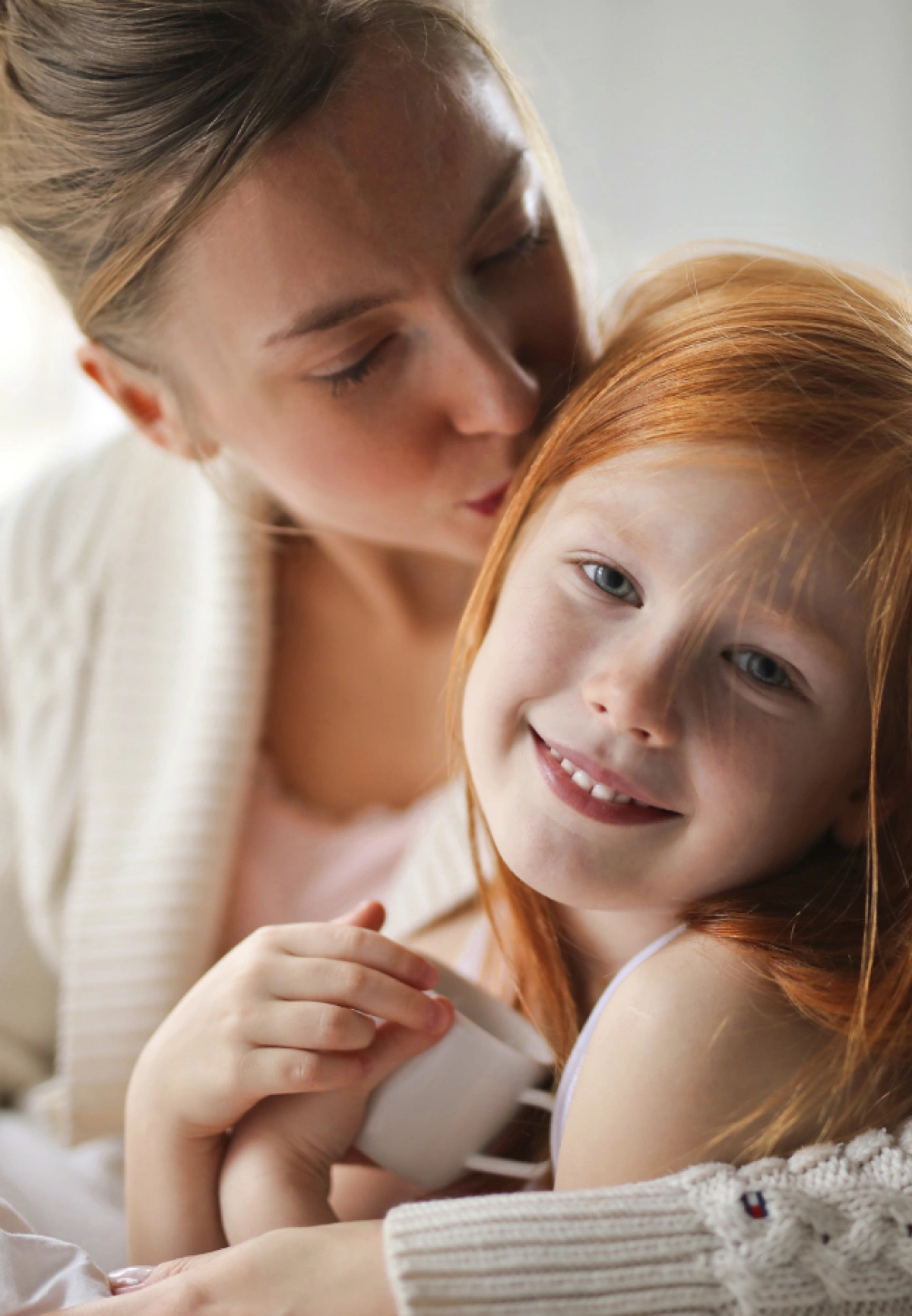 A warm close-up of a parent kissing a smiling child, reflecting compassionate, family-centered allergy and immune care at Global Allergy Immune Network in Murray, UT.