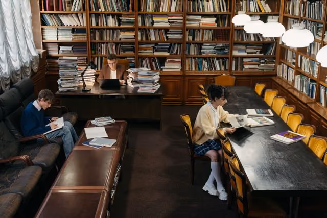 A woman in a yellow sweater is reading a book.