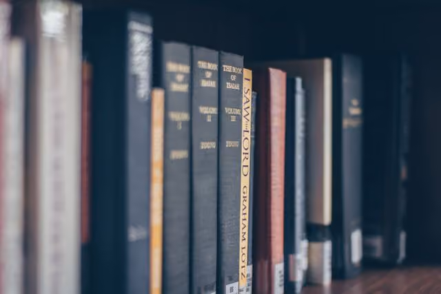 A row of books with one of them titled The Book of Common Prayer.