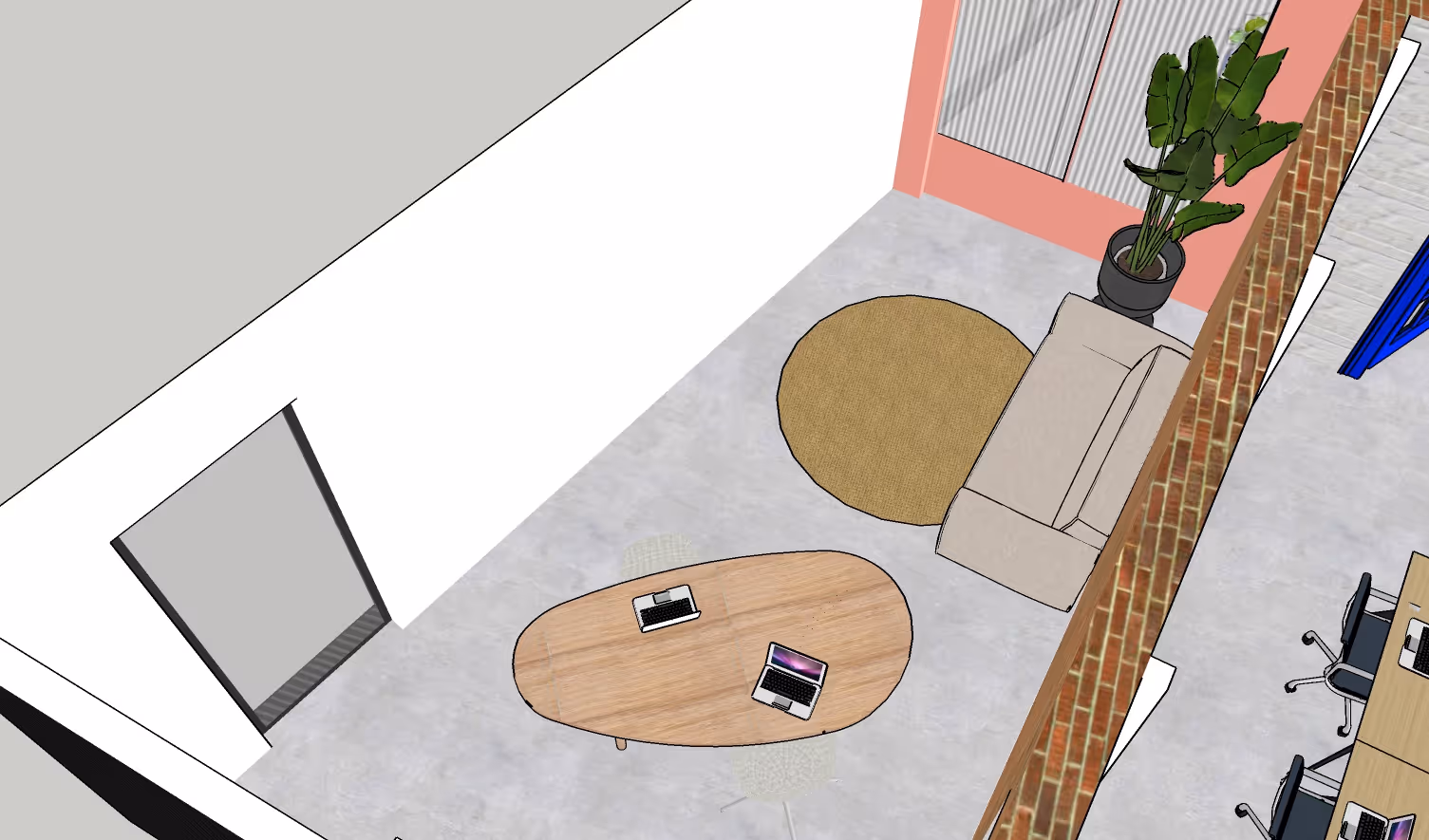 Top-down view of a modern small office area with an oval wooden table holding two laptops, a beige couch on a round brown rug, and a potted plant in the corner.