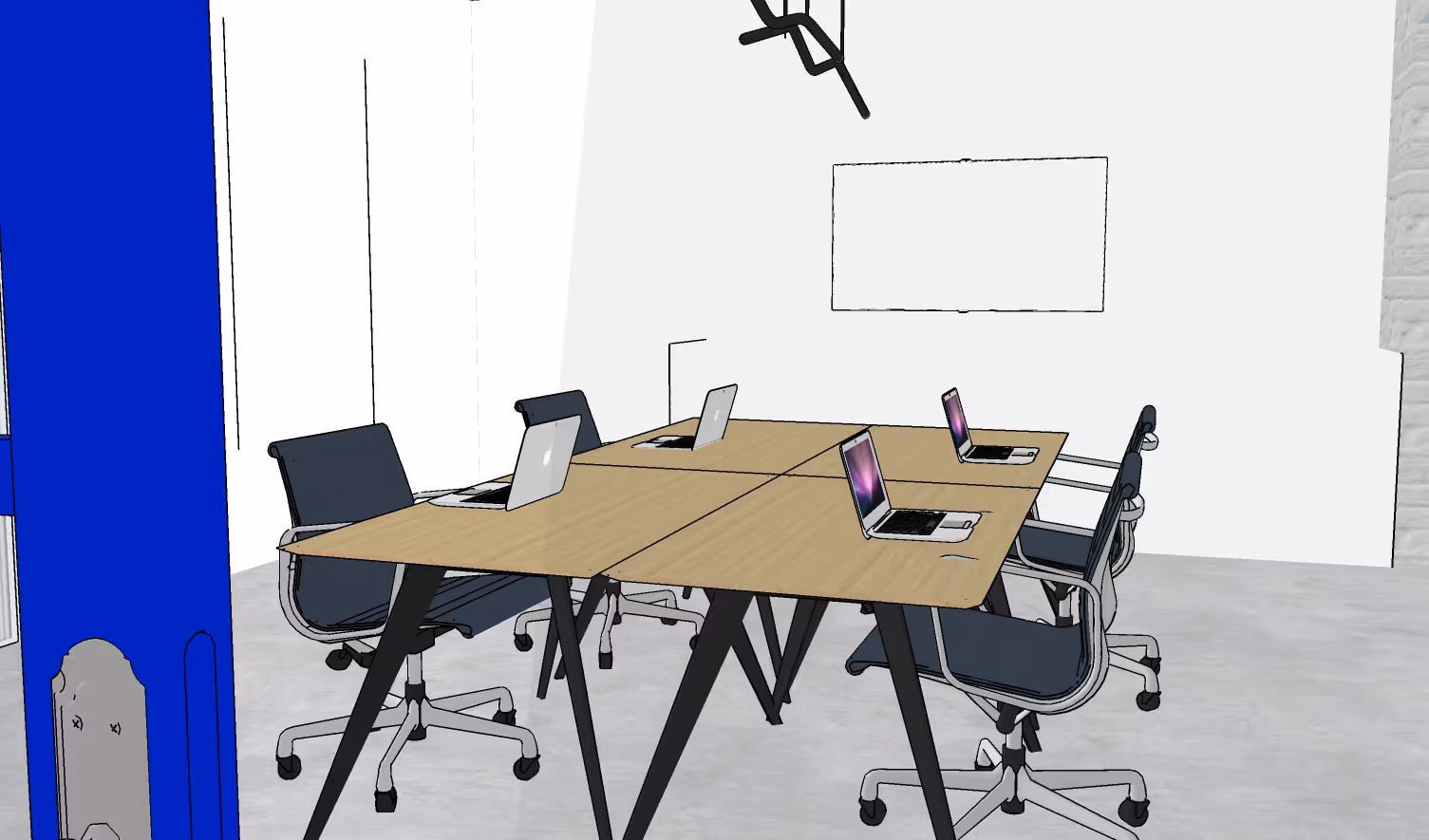 Modern coworking space with four laptops on a wooden table surrounded by black office chairs.