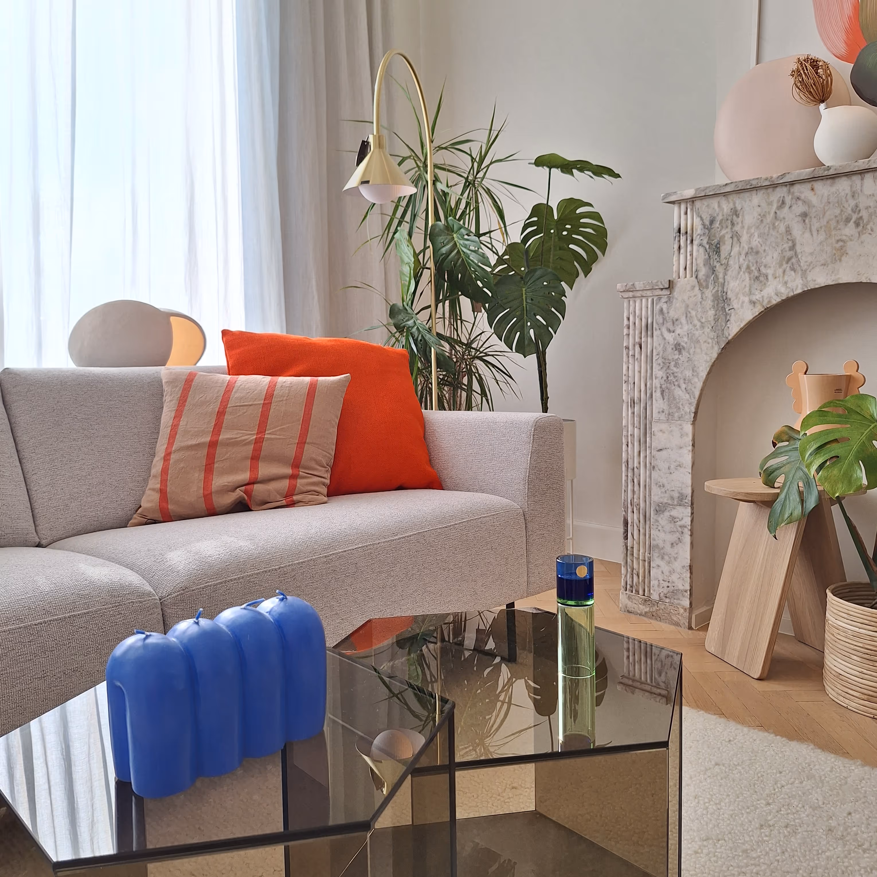 Foto van een interieur, beige zetel, oranje kussens, openhaard, glazen.