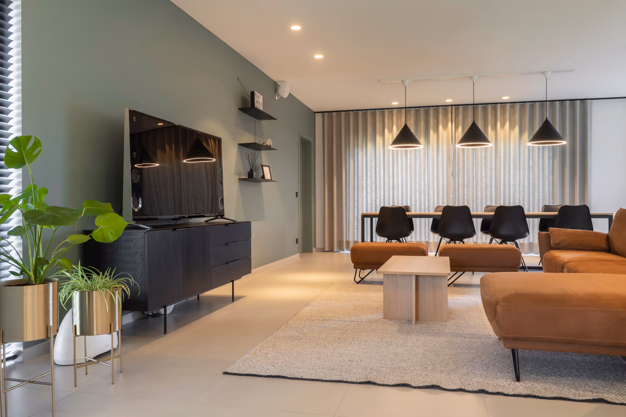 Modern gerestylde woonkamer met een tv meubel, zetel, en eettafel.