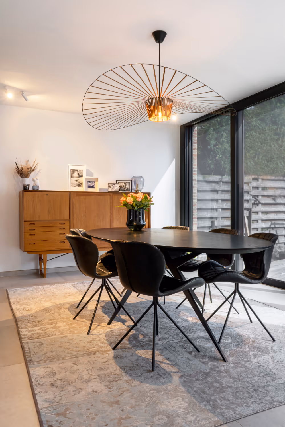 Stijlvolle restyling van een woonkamer met een zwarte eettafel en houten kast