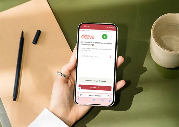 Mano che tiene uno smartphone con il modulo di prenotazione online di Deeva aperto