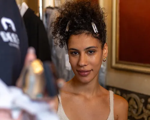 Modella con capelli ricci raccolti con mollette, nel backstage di un evento
