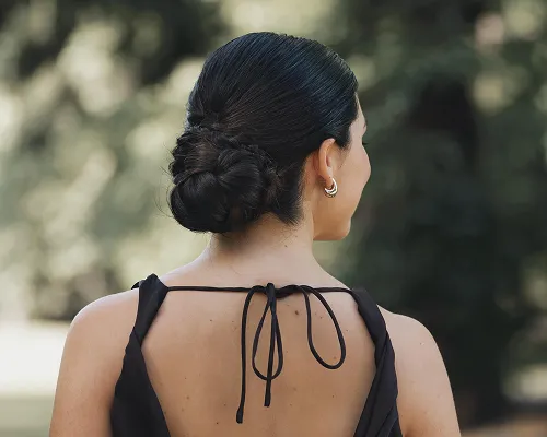 Chignon basso su capelli scuri per una cerimonia, su un abito nero con schiena scoperta