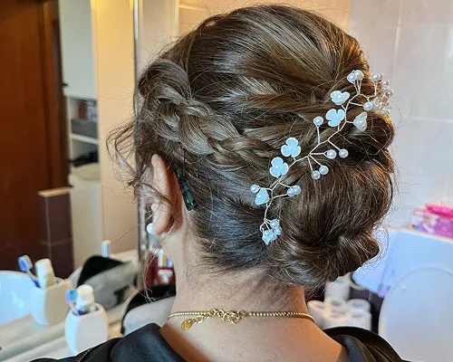 Raccolto intrecciato con fermaglio di fiori azzurri e perle, visto da dietro