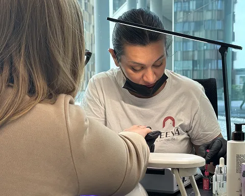 Onicotecnica Deeva fa la manicure a una cliente in un ufficio con grandi vetrate
