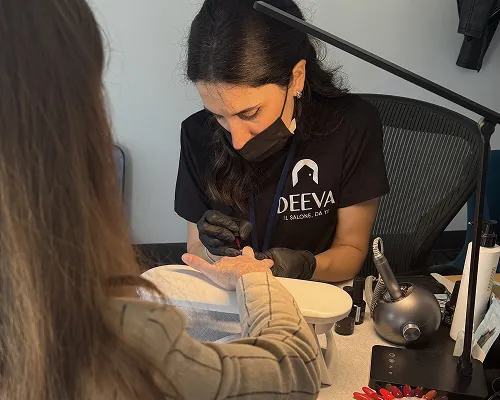 Onicotecnica Deeva fa la manicure a una collega alla scrivania di un ufficio