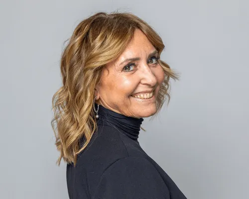 Donna sorridente con taglio medio e piega mossa sui capelli biondi, dolcevita nero