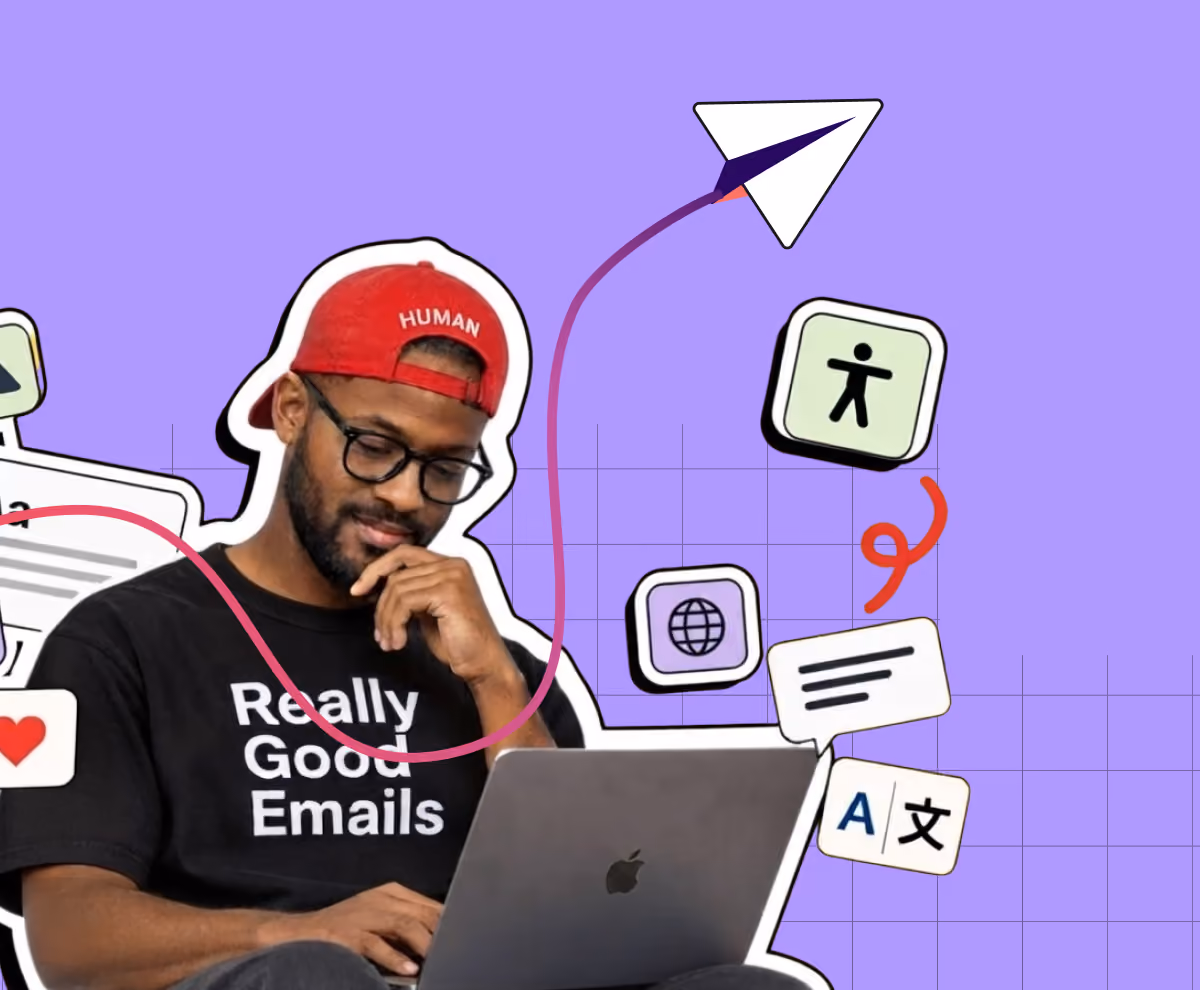 Man wearing glasses and a red cap with the word HUMAN, sitting and working on a laptop with a black t-shirt that says Really Good Emails, surrounded by icons including a paper airplane, accessibility symbol, globe, chat bubble, and translation symbol on a purple grid background.