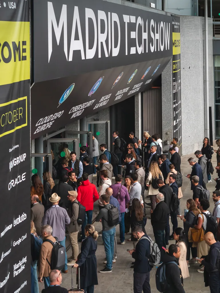 Crowd of people entering the Madrid Tech Show under a large banner with event categories.