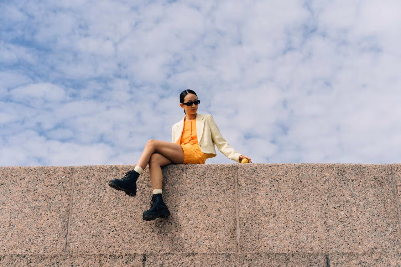 Woman in an orange dress sitting in a wall.