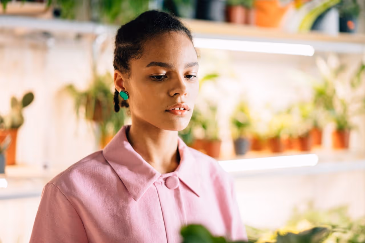 Woman holding a plant and looking down.