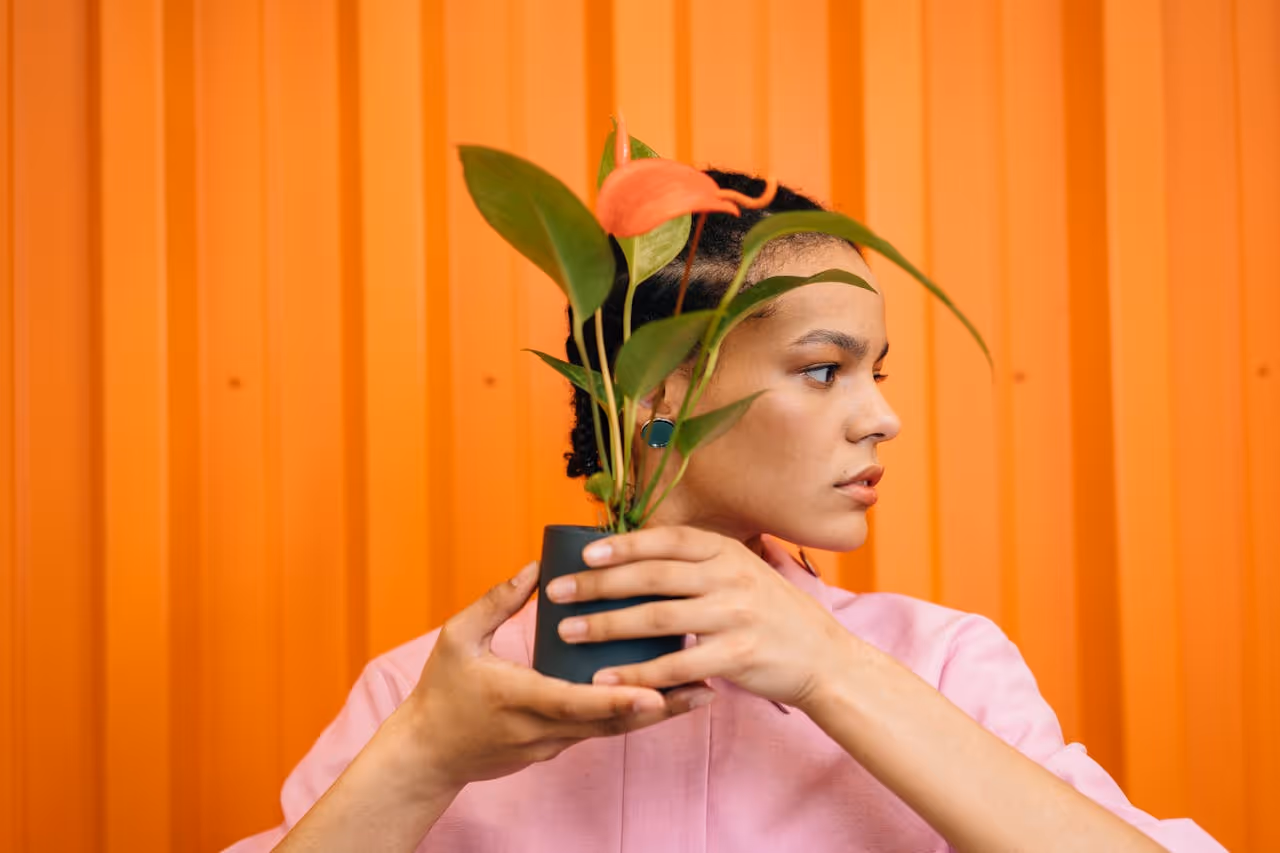 Woman covering her face with a plant.