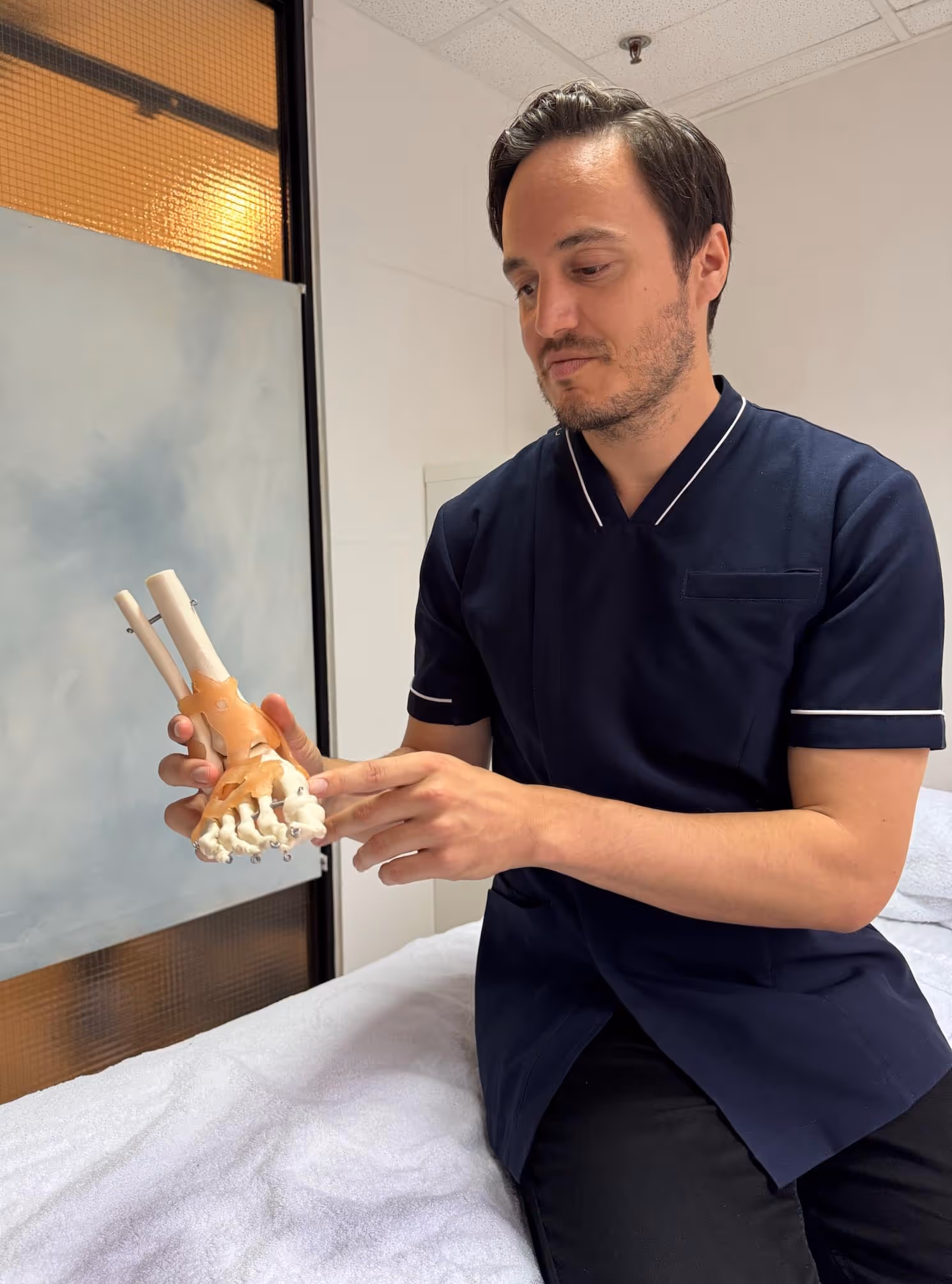 Osteopathic practitioner at City Osteopathy using anatomical spine model for patient education, demonstrating the clinic's approach to helping patients understand their body's interconnected systems and the osteopathic treatment process