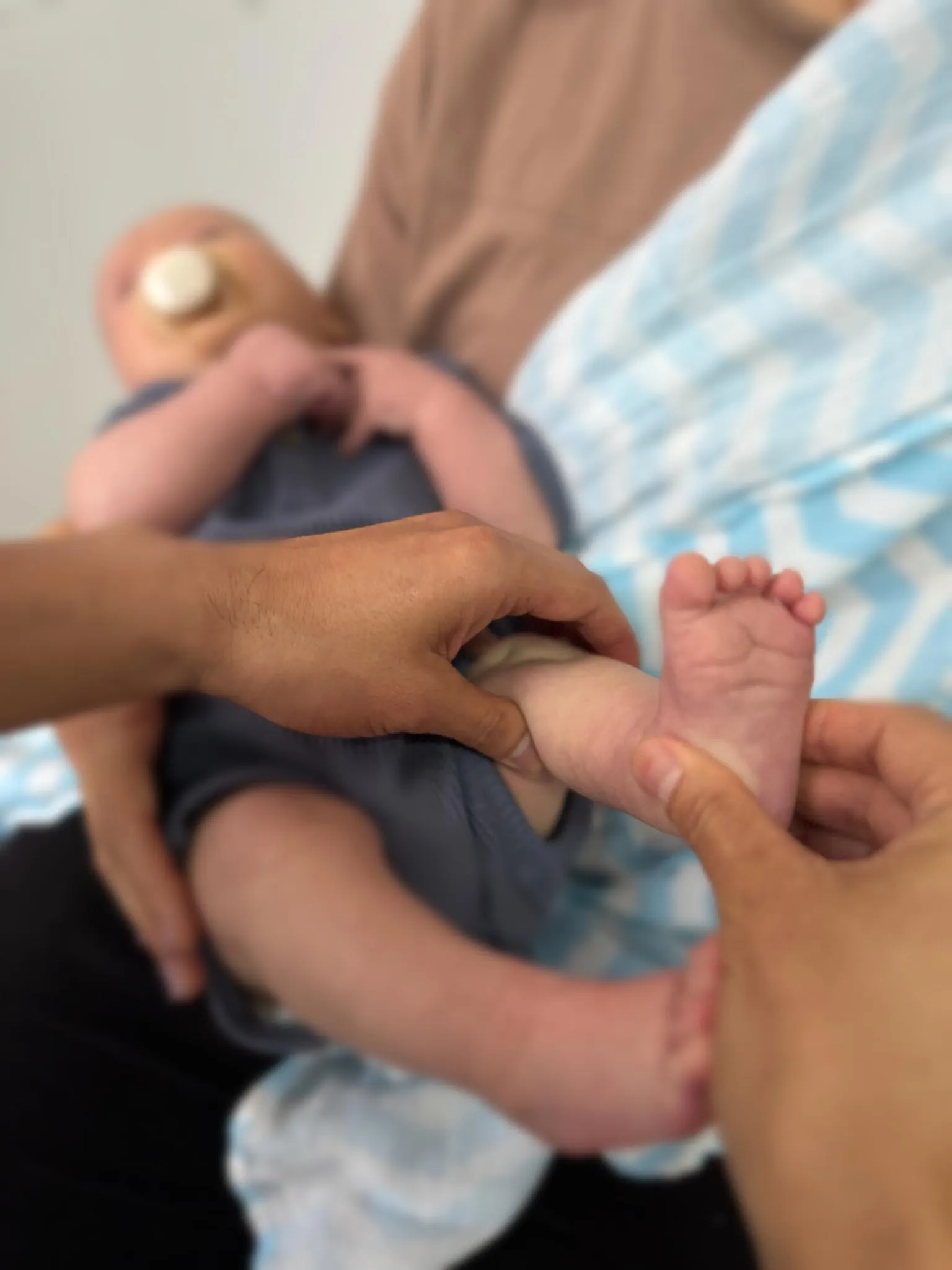 Paediatric osteopathy treatment at City Osteopathy showing practitioner providing gentle care to infant's legs and hips, demonstrating the clinic's specialized osteopathic approach for babies' developmental and comfort needs