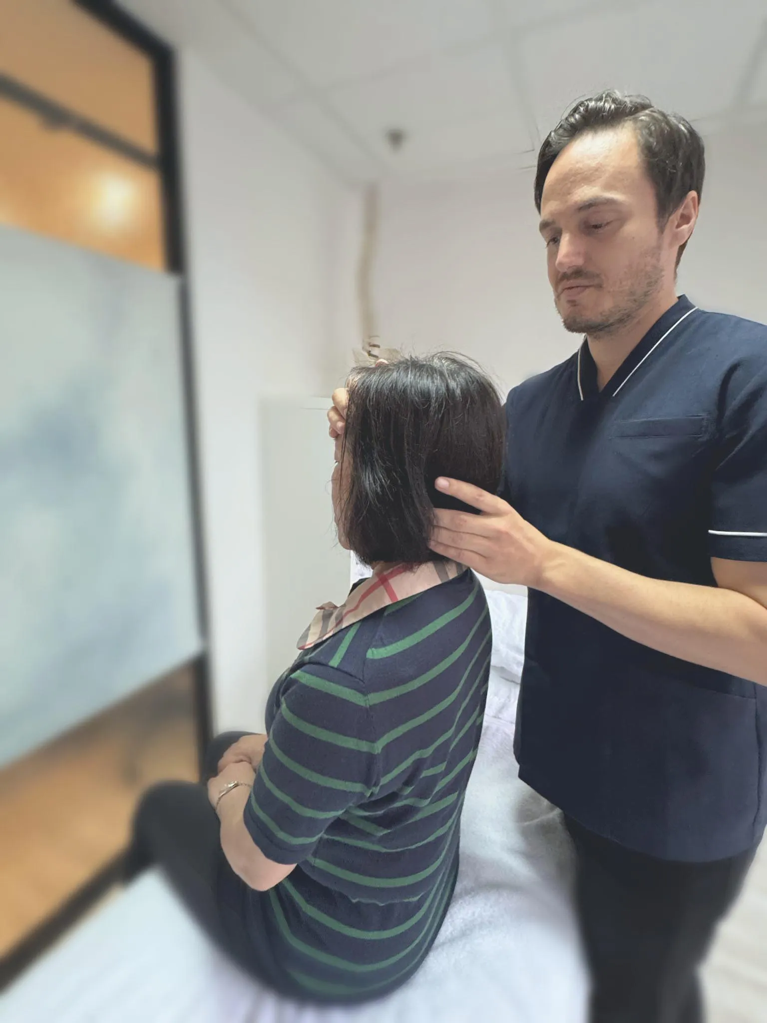 Osteopathic practitioner at City Osteopathy performing gentle cranial osteopathy on patient, demonstrating the clinic's hands-on manual therapy approach for headaches, neck pain, and postural issues