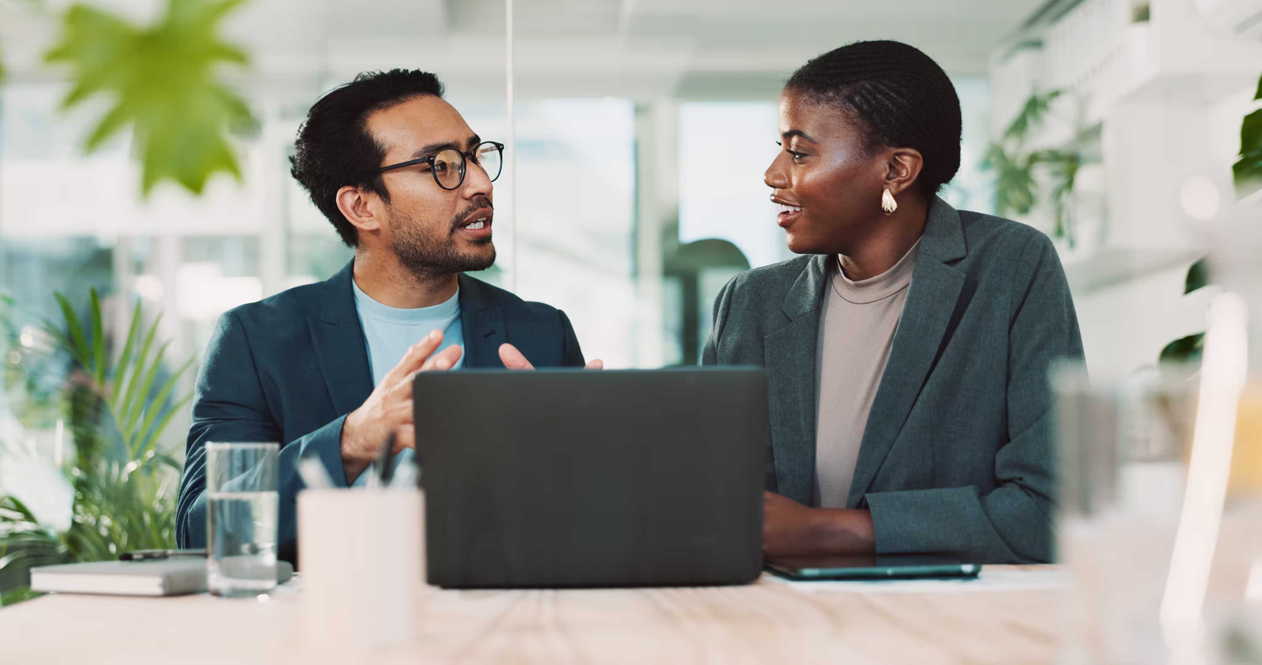 A manager and employee talking by a laptop.