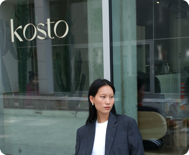 Woman standing in front of Kosto’s glass storefront in Brussels.