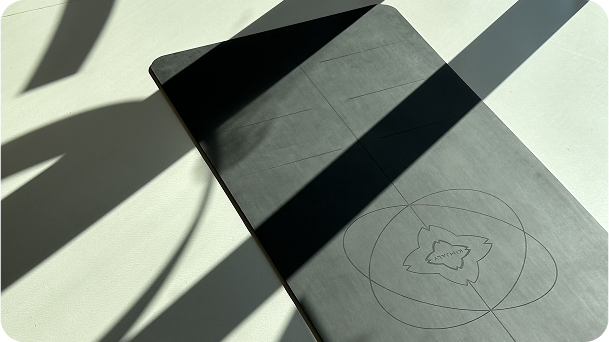 A yoga mat with minimalist lines and floral engraving, bathed in soft sunlight and graphic shadows.