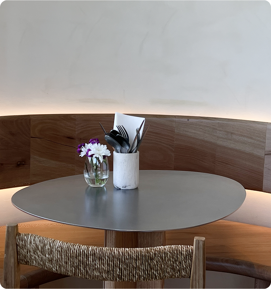 Minimal round table at Kosto café, set with fresh flowers and utensils.