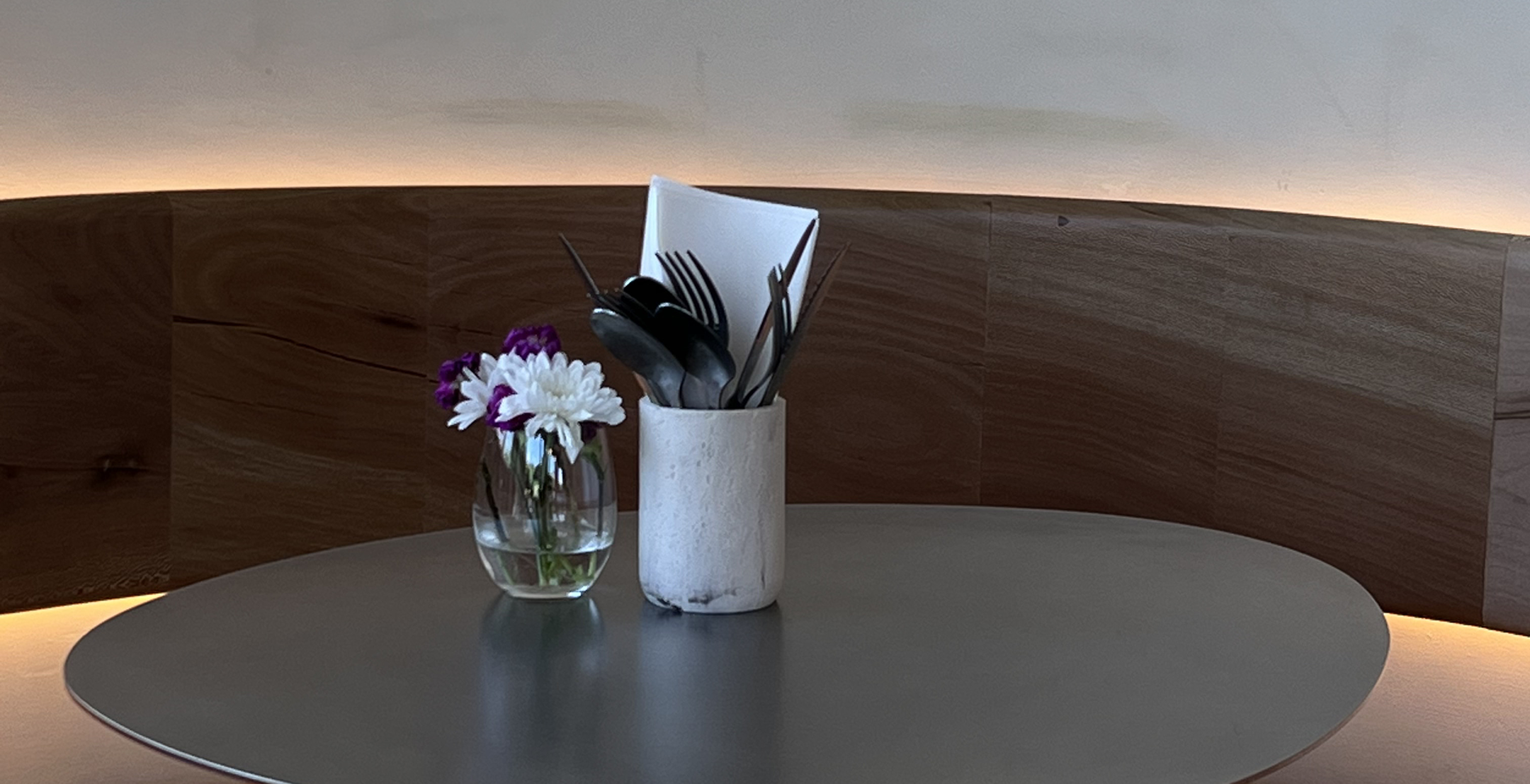 Minimal round table at Kosto café, set with fresh flowers and utensils.