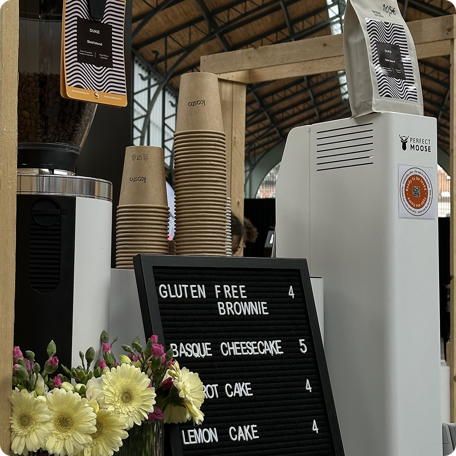 Inside Kosto cafe with a coffee machine setup at local market with floral decor.