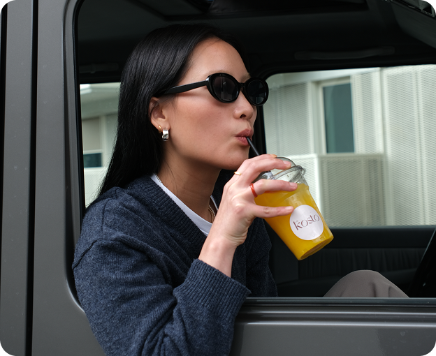 Stylish woman sipping fresh juice from the car window.