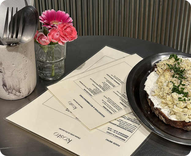 Tabletop at Kosto with printed menus, flowers and a dish