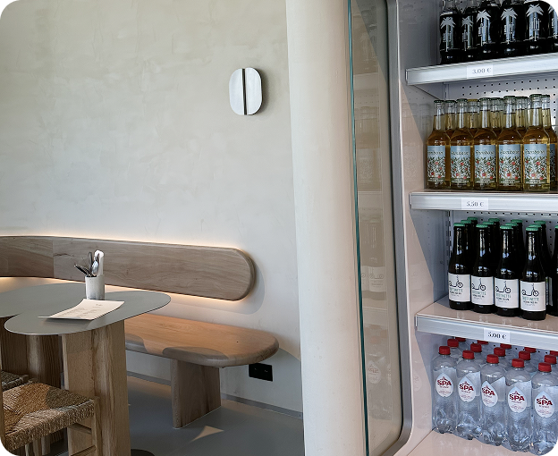 Warm and minimal seating corner inside Kosto, with shelves of craft drinks.