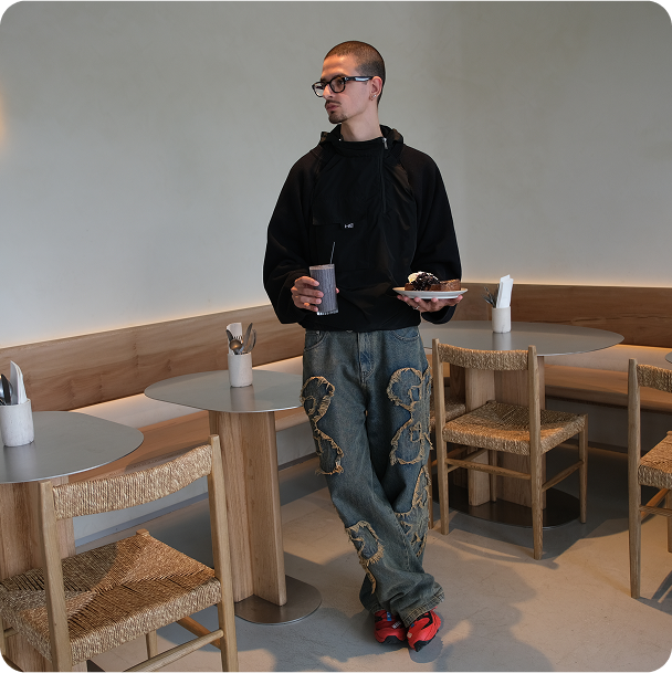 Casual moment inside Kosto: man standing with coffee and pastry.