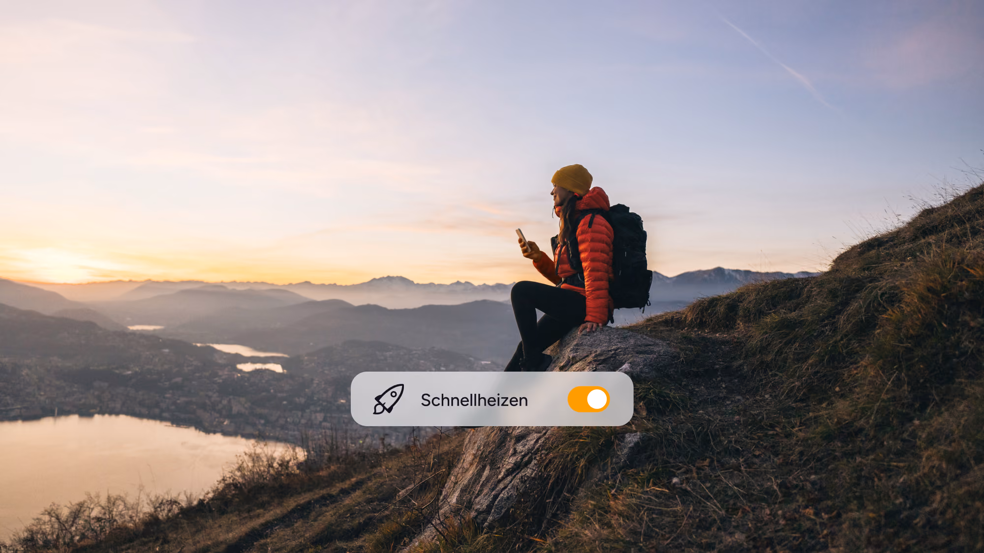Person auf einem Berg bei Sonnenuntergang, die die tado° App auf einem Smartphone nutzt