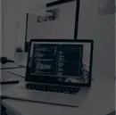 Workspace setup featuring a laptop displaying code, symbolizing digital infrastructure services, with a dual monitor in the background for enhanced productivity