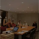 A team engaged in a collaborative meeting, with a presenter using a projector and laptop, symbolizing staff augmentation and teamwork in a professional environment.
